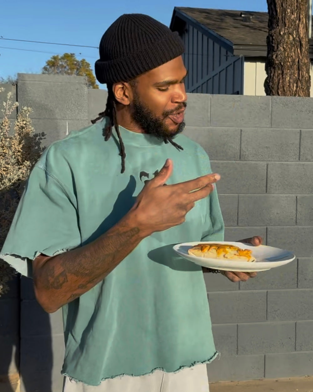 A man standing outside, eating a Bad Hambres burrito from a plate