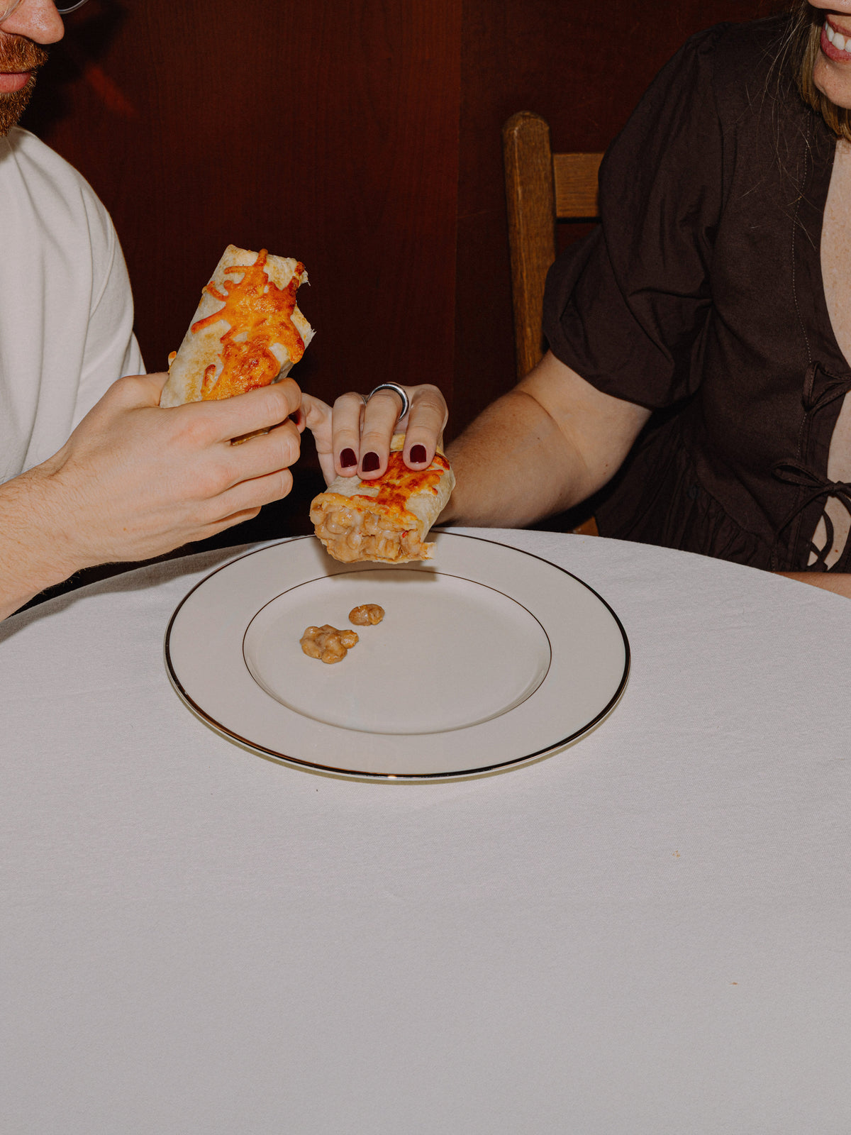 2 people sitting at a table, enjoying a plate of Bad Hambres burritos
