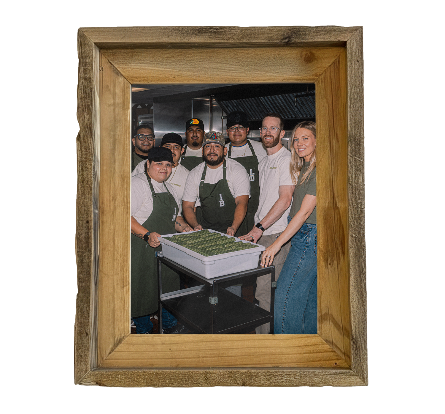 A wooden framed picture of the Bad Hambres team in their kitchen with a tub of burritos