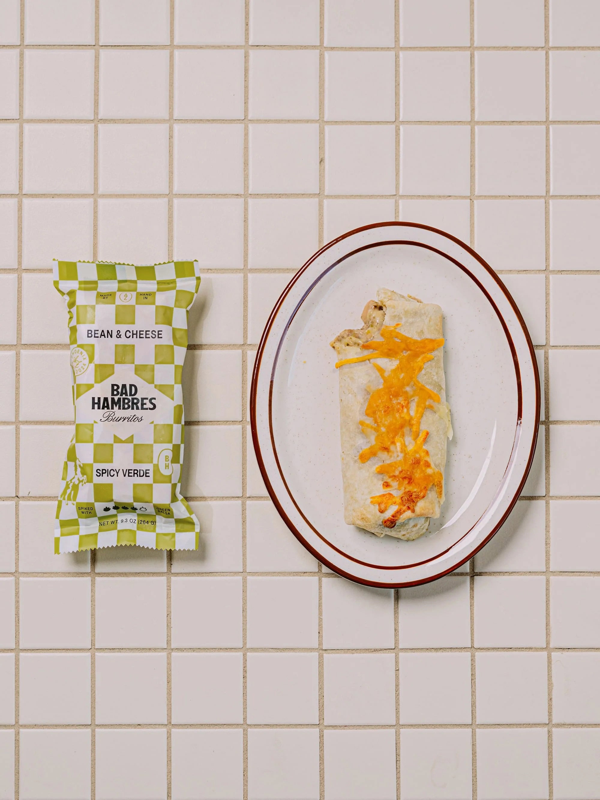 Top down shot of a plate of a Bad Hambres Spicy Verde burrito with its packaging on the side